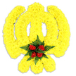 A reverent floral Khanda rendered in sunshine yellow, carefully sculpted from hundreds of small, tightly clustered yellow chrysanthemums to recreate the sacred Sikh emblem against a pure white backdrop. The arrangement follows the Khanda's graceful geometry: a central double-edged khanda sword, the circular chakkar (chakram) and the two crossed kirpans at the base, all defined by dense, plush yellow blooms that give the symbol a soft, tactile, almost quilted surface. At the heart of the piece, where the circle and sword meet, a concentrated cluster of five deep red roses is tucked into a bed of dark green fern fronds, the velvety rosebuds and glossy foliage producing a vivid focal contrast that reads like a heartbeat at the emblem's core. A faint, cool-flash of shadow beneath the tribute confirms its physical presence and suggests careful studio lighting, while the white negative space lets the golden tones and the crimson centre sing with quiet dignity. Texturally the chrysanthemums read as soft, ruffled petals layered like sunlit fabric, the roses offering firmer, classic curves, and the ferns a feathery counterpoint; together they create both visual clarity and a comforting tactility. The scent is implied - a gentle floral lift with green, fern-like notes that would be subtle in a memorial setting. As a floral artist serving Cranham and neighbouring Upminster and Hornchurch, I visualise this piece positioned at a gurdwara doorway, a community remembrance, or a funeral tribute, meant to honour Sikh faith and cultural heritage with precision, respect and local care.