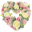 A tender, heart-shaped floral wreath dominates the image, photographed against a bright white background so that its soft colours and thoughtful details stand out with clarity. The heart itself is generously filled with flowers, leaving no bare spaces, which gives it a plush, cushion-like appearance that suggests gentle support and care. Creamy yellow and ivory roses are distributed evenly through the design, their tightly layered petals curling outward in beautiful, velvety spirals that attract the eye and anchor the composition. Between them, delicate pastel pink carnations nestle in generous clusters, their ruffled edges layering over one another to form a soft, textured blanket of colour. Punctuating this pastel mix are deeper pink and mauve lisianthus blooms, their open, trumpet-shaped flowers introducing a slightly richer tone and graceful, flowing lines. Small, yellow-green buds are scattered subtly throughout the wreath, hinting at fresh growth and the continuation of life even amidst loss. Woven amongst all these blossoms are sprigs of silvery-green eucalyptus, their smooth, rounded leaves bringing a gentle, cool contrast to the warm creams and pinks, while also helping to shape and support the heart's clear outline. The emotional impression is one of quiet sympathy, remembrance, and enduring love, a design perfectly suited for funerals, memorials, or condolence offerings delivered across Cranham and the surrounding areas. This heart-shaped tribute feels like a floral embrace, ideal for resting beside a casket, on a stand near the altar, or in a family home where loved ones gather to remember and reflect.